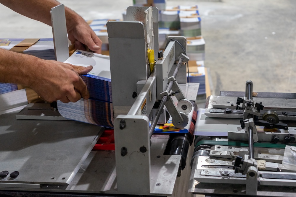 Operator loading printed pieces into a feeder on a Solo Printing mailing line