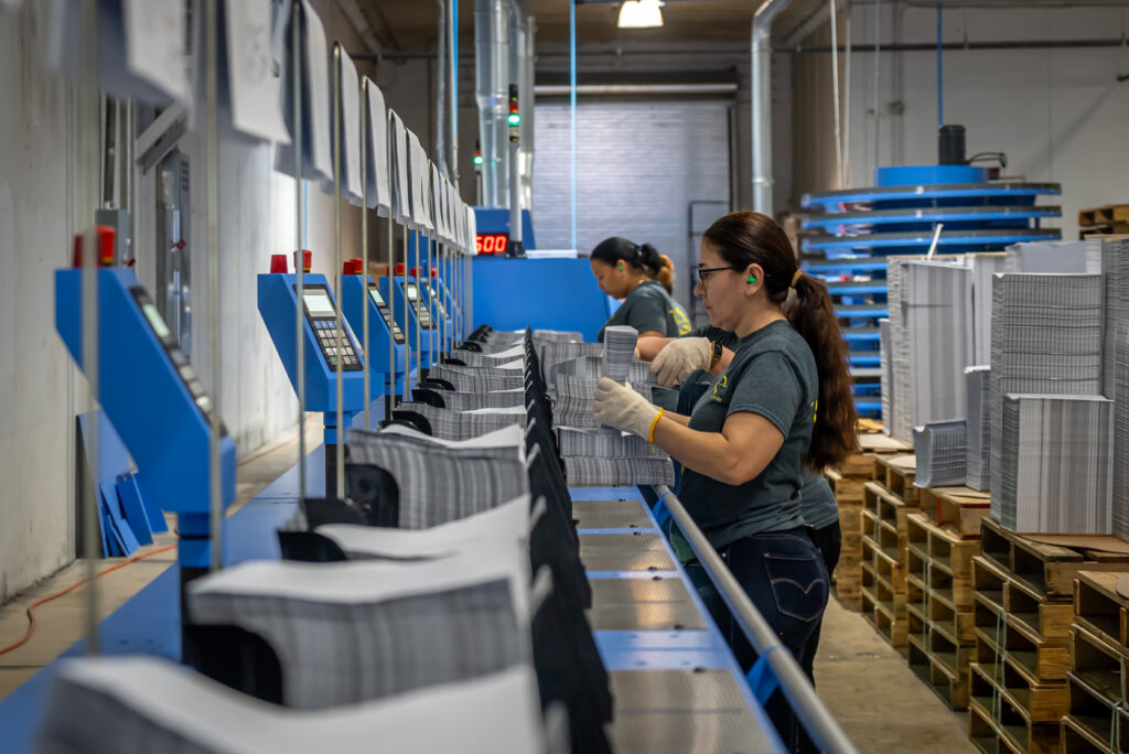 Solo Printing team members working a bindery line with stacks of finished pieces
