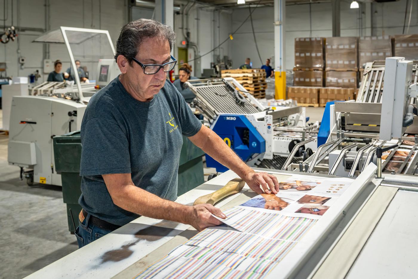 Solo Printing operator inspecting a printed brochure sheet in Miami
